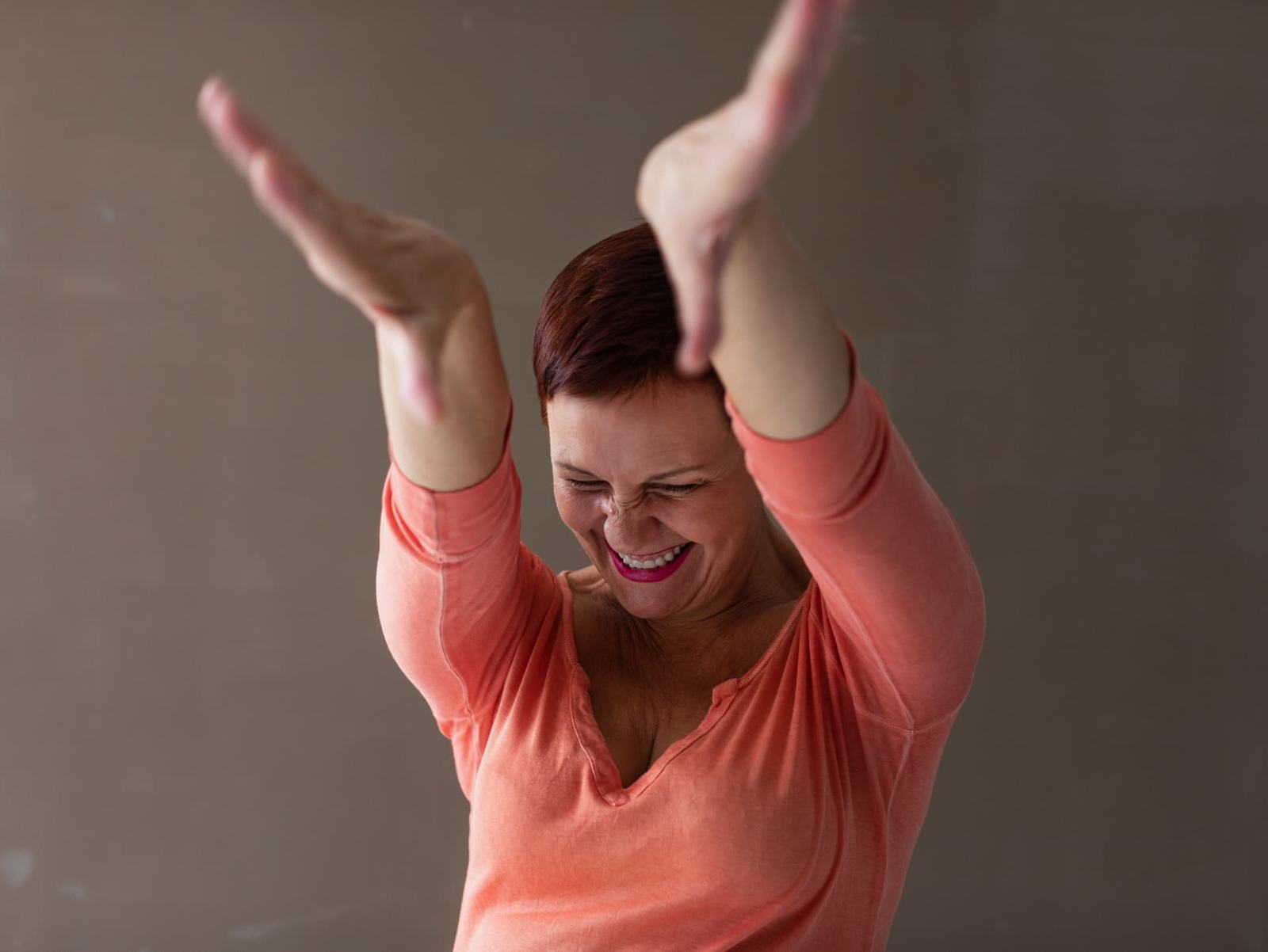 Mujer sonriendo con los brazos en alto, celebrando