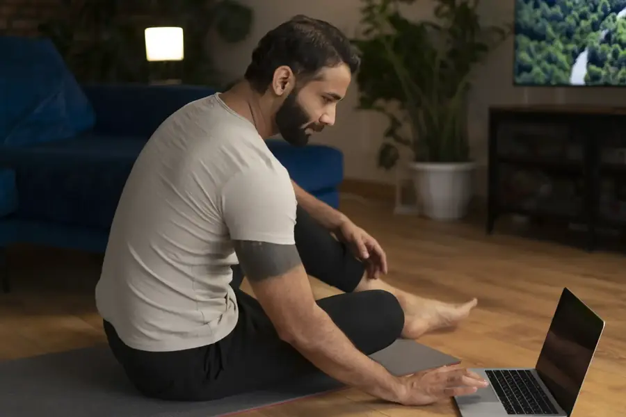 Hombre meditando en casa frente a su laptop