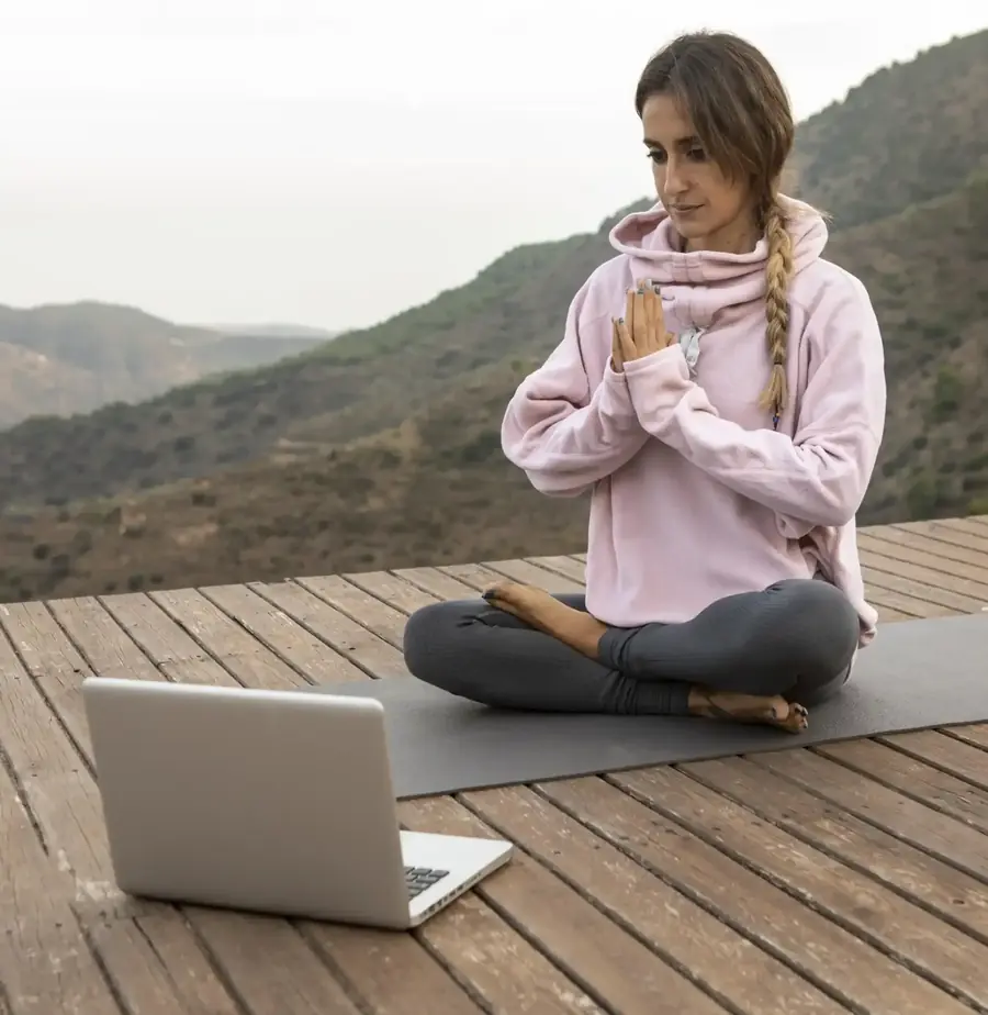 Mujer meditando en un deck frente a la montaña