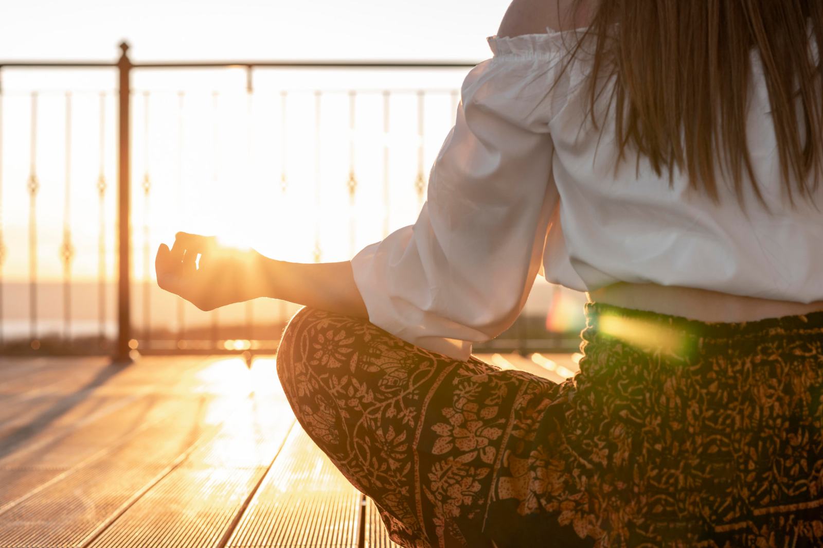 Mujer meditando al atardecer con la luz del sol entre las manos